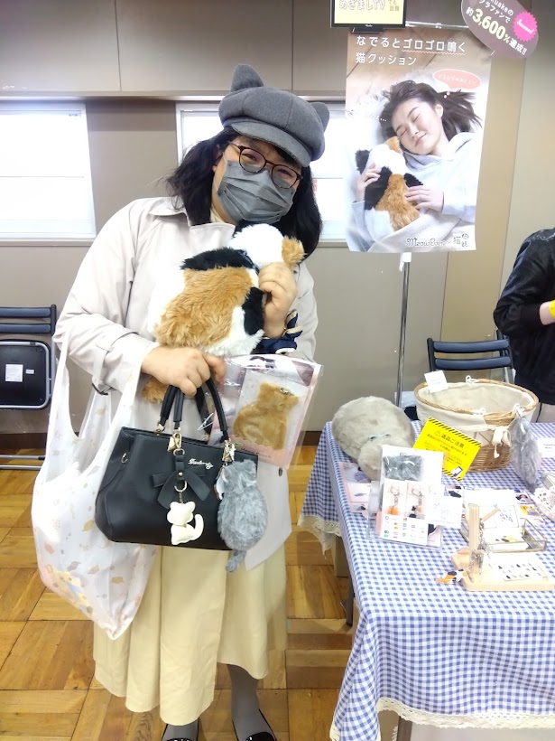 CocoMeowのブース前でアプリコットの仔猫を手にして立つ北村由衣