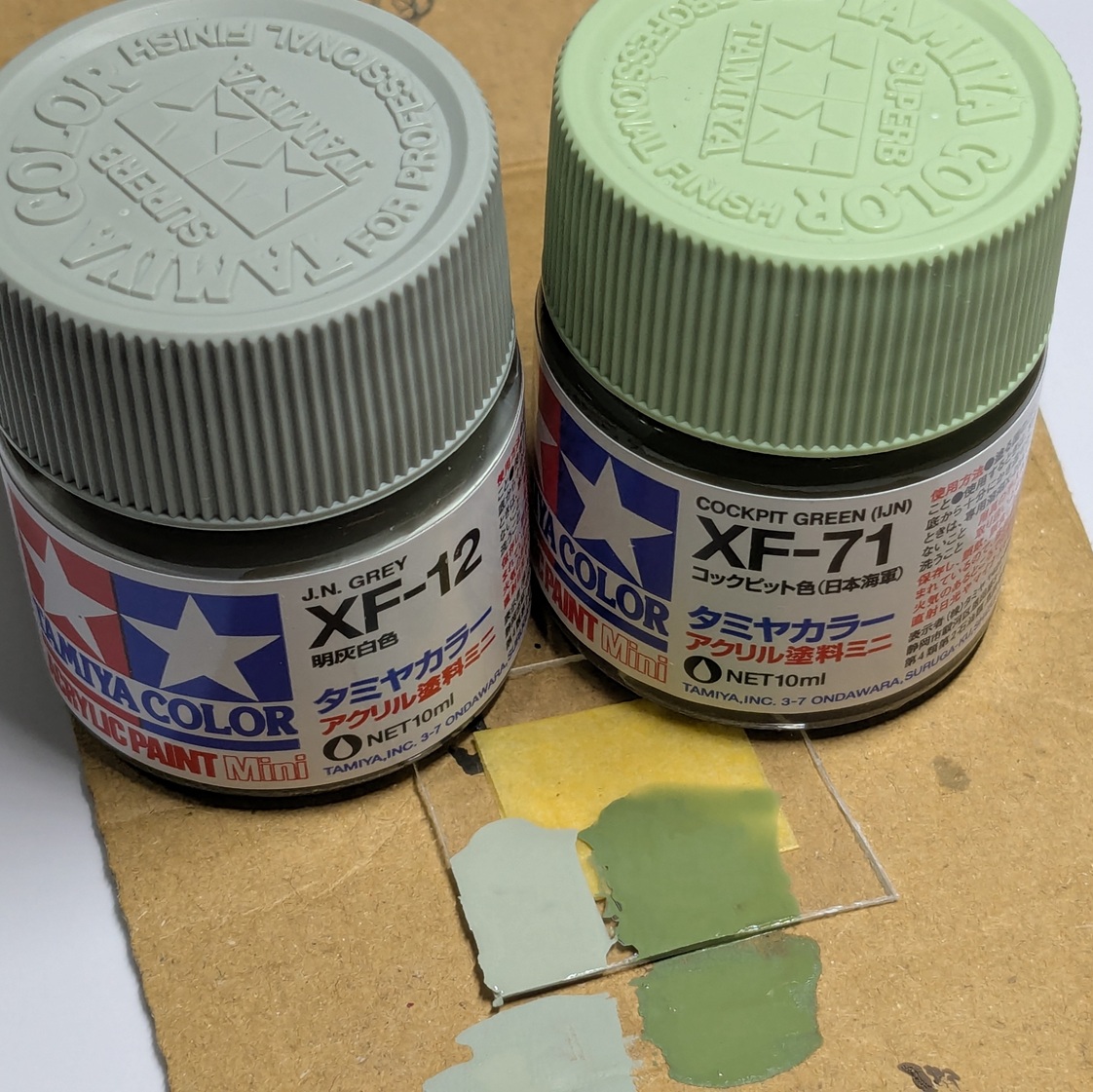 明灰白色とコックピット色の塗装比較をした写真。プラ板と段ボールにそれぞれの色が塗られている