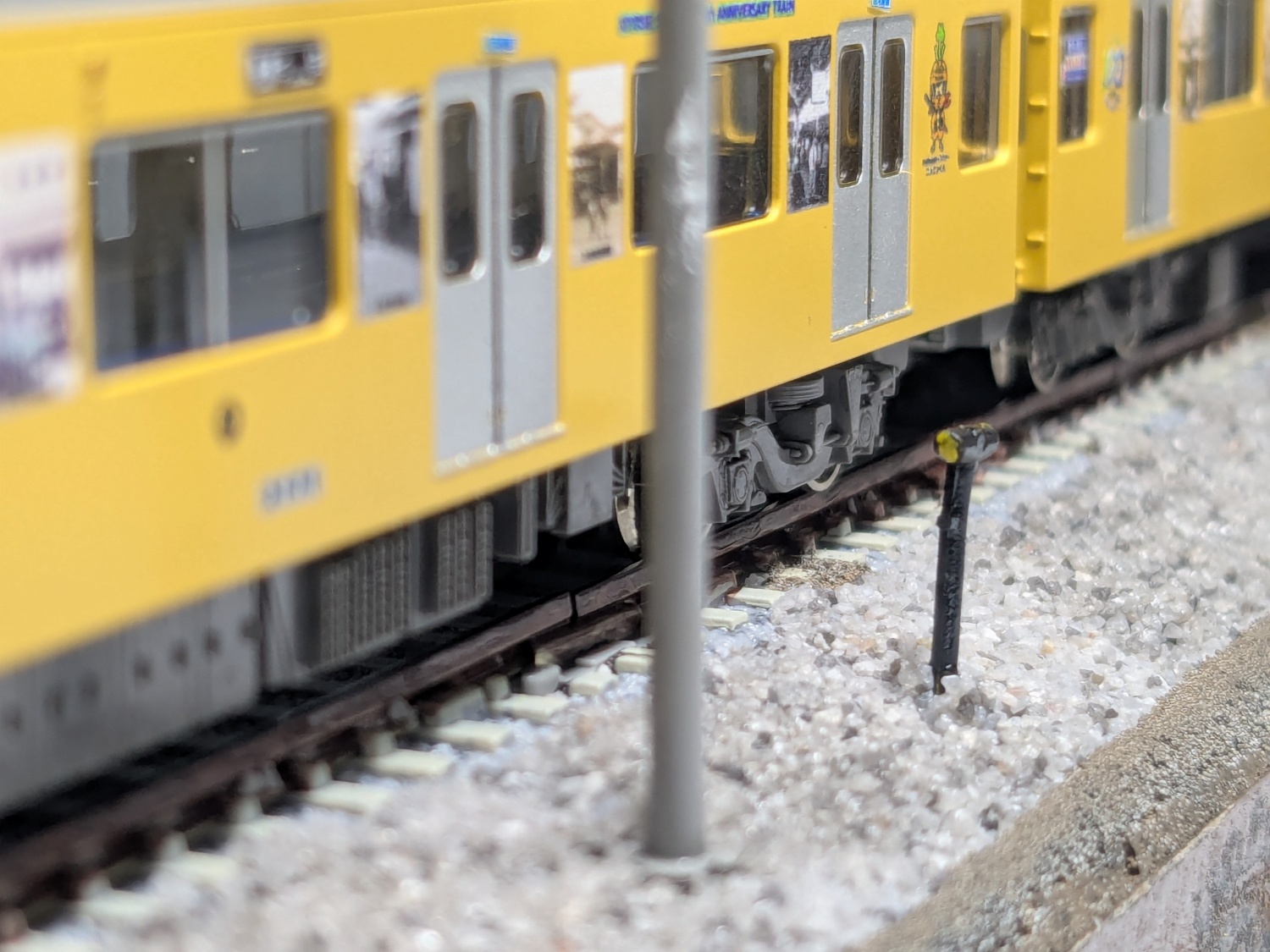 レイアウトに設置された列車接近表示器の写真。本体が黒色、灯火部分が黄色に塗り分けされている