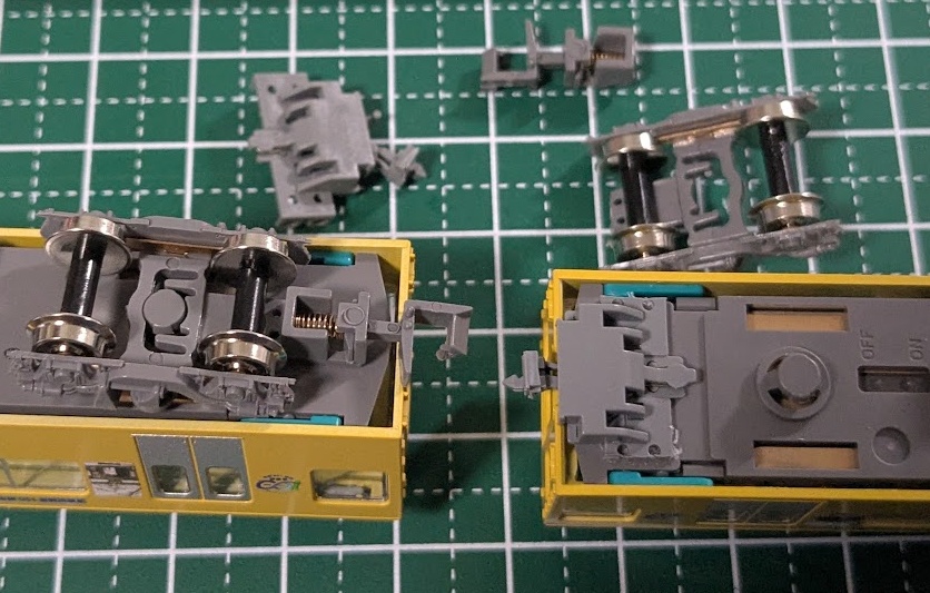 模型が2両、裏返しにされている写真。片側は未施工状態、もう片方は連結器の交換途中