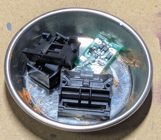 5つの構成部品に分解された運転室部分を塗装用トレーに入れた状態の写真。照明用の電子基板や、光を遮るプラスチック製パーツが写っている